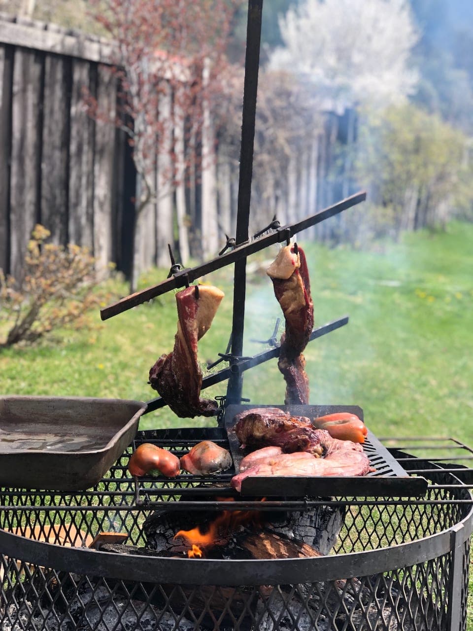Asado steak hanging over open coals