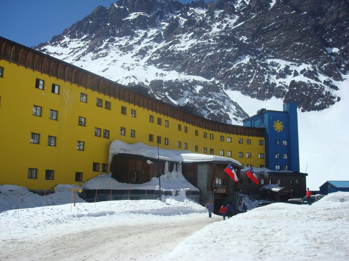 The yellow Hotel Portillo below snow-covered peaks