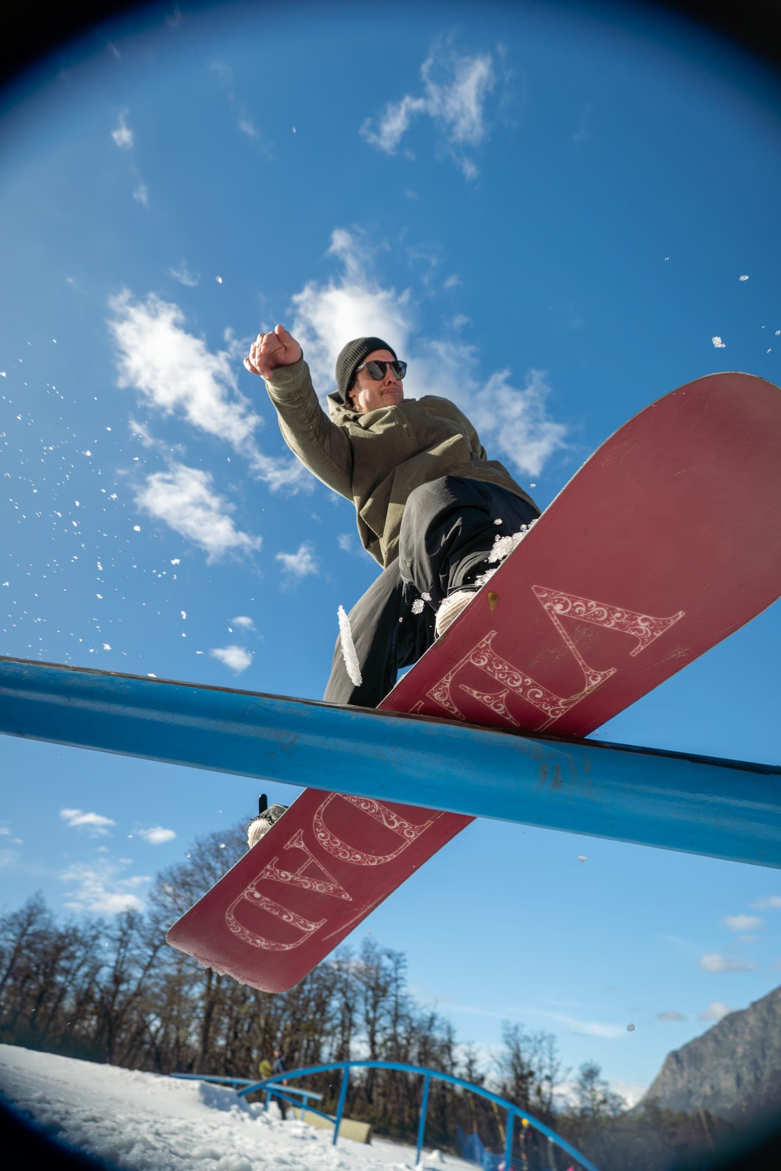 Snowboarder sliding a rail with snow spraying from the board