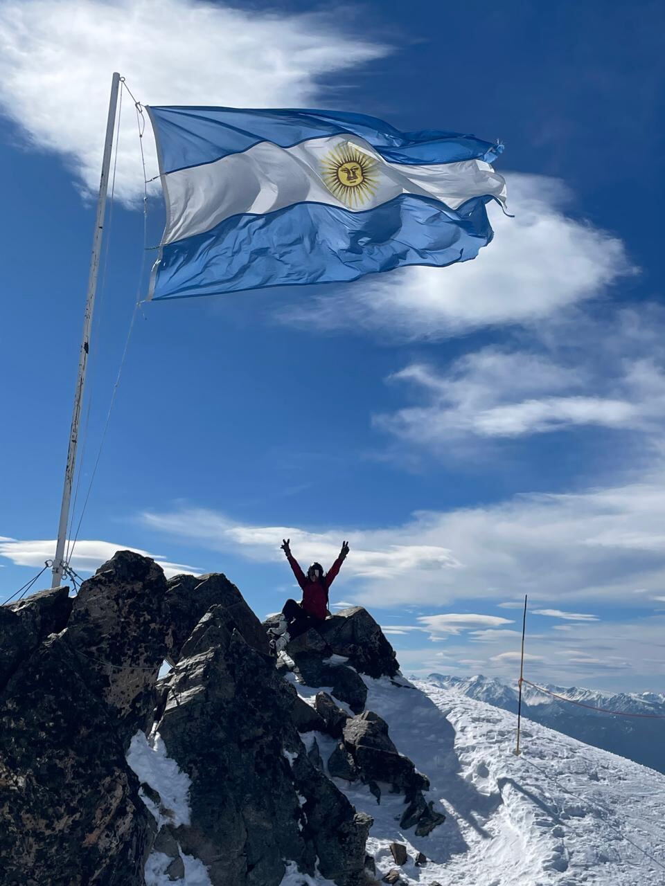 Argentine flag flying above snowy mountain terrain in Bariloche
